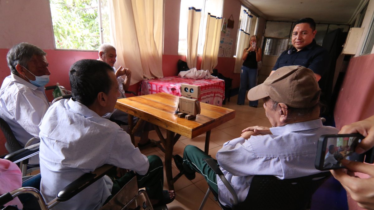 Adultos mayores escuchan y conversan con el asistente de IA durante la actividad organizada por estudiantes e investigadores universitarios.