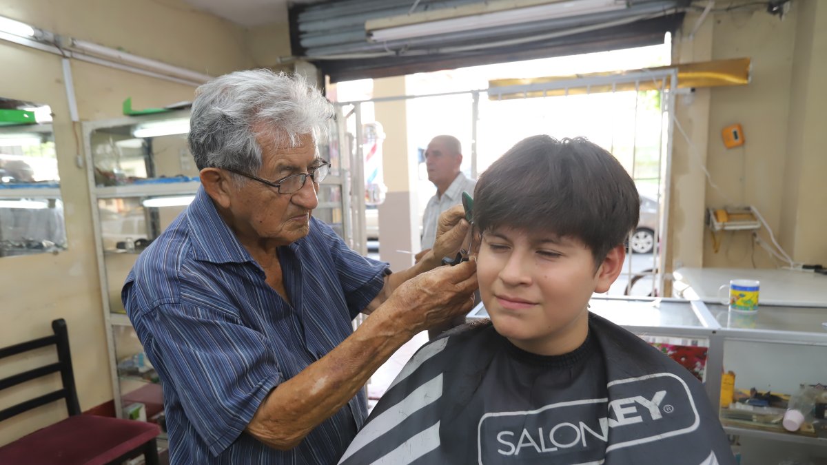 Don Jorge Barros le corta el cabello a Nicolás, quien prefiere la tijera frente a las tendencias actuales.