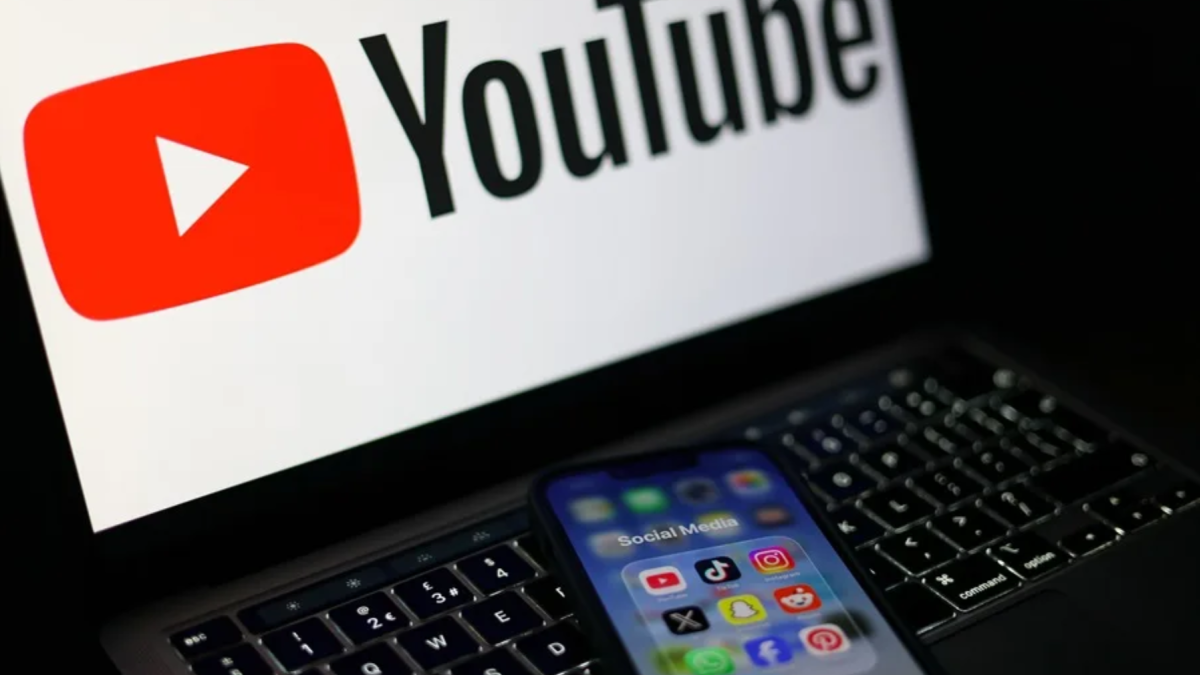 Pantalla con el logo de YouTube, propiedad de Alphabet, y un móvil con aplicaciones de redes sociales como Instagram y Facebook