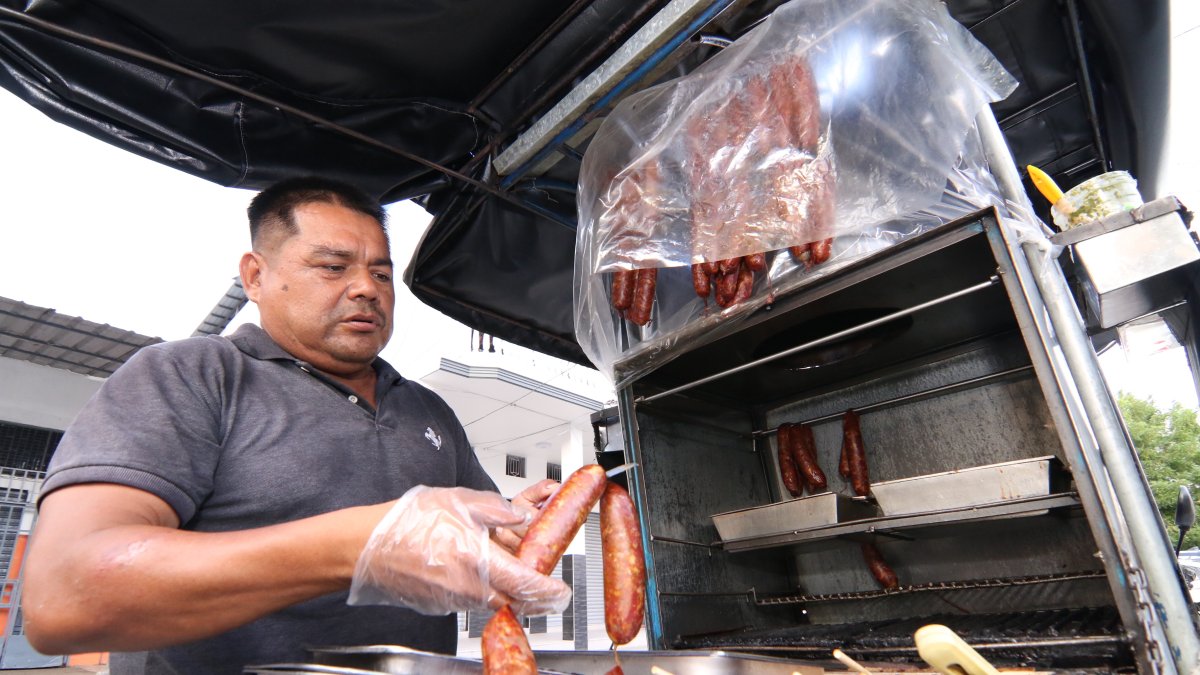 Orlando usa guantes de plástico para servir sus chorizos.