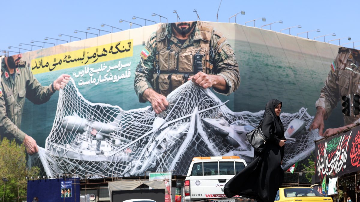 Una mujer pasa junto a una valla con el mensaje 