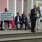Liliana Silva sostiene un cartel de rechazo, mientras Viviana Veloz (der.) es reconocida en Santo Domingo.