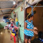 Mujer observa con preocupación la entrada de su vivienda inundada en Esmeraldas, mientras intenta proteger sus pertenencias del agua acumulada en el interior.