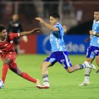 José Marrufo (c) de Macará disputa un balón con Jorge Valencia (i) de América .