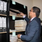 El fiscal César Peña revisa los archivos encontrados en la estantería de su despacho.
