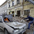 Personas y soldados limpian los escombros junto a automóviles y edificios dañados por un terremoto en Petrinja, Croacia.