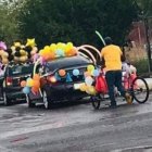 El padre de familia que lleva a su hijo en el triciclo que adornó para participar de la fiesta de fin de curso.