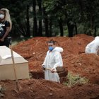 Un trabajador entierra a una víctima de covid-19, mientras familiares se lamentan en el Cementerio Vila Formosa, en Sao Paulo (Brasil).