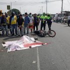 Agentes de tránsito y curiosos observan el cadaver que yace bajo una manta.