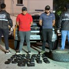 Los dos sospechosos junto a policías y los paquetes de droga que fueron incautados.