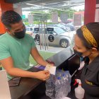 Joven presentando el carné de vacunación a la entrada de un gimnasio.