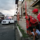 Vecinos de la víctima miran cautelosamente el arribo de equipos policiales a la escena del crimen.