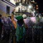 Mujer frente a los policías en marcha por el 8M en Quito.