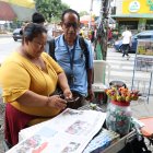 La canillita Ingrid Andrade le enseña al lector Bolivio Cali como escanear el código QR.