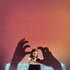 Pensive young attractive girl reading book and sitting on chair isolated on a orange background