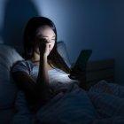 Chica de 14 años mira su teléfono móvil antes de dormir