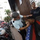 Darío corta el cabello en medio de la Bahía, al pie de una estación de Metrovía.
