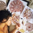 Jasmine Carter junto a algunas de sus pinturas hechas con su período.