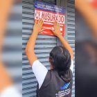 Funcionaria de Arcsa coloca el sello de clausura en la puerta de un supermercado en Ibarra.