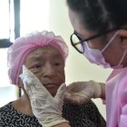 Robertina Moscoso siente alivio y se distrae mientras le aplican cremas para hidratar su piel. Ella vivió con cáncer por muchos años.