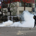 Un manifestante camina a través del humo de granadas de humo aturdidoras .