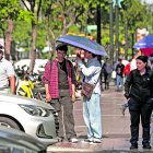 Ciudadanos se cubren con un parasol del intenso sol.