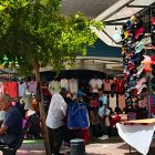 Un vendedor informal ofrece ropa justo frente a locales establecidos dedicados al mismo rubro.