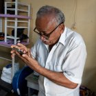 Víctor Guarín mientras mira su teléfono con ayuda de unos lentes, pero con una escasa visión.