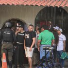 Agentes policiales y vecinos se congregan bajo la lluvia en el barrio San Francisco, tras el ataque armado que dejó un hombre muerto y un niño herido.