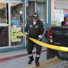 Un agente coloca una cinta para evitar que los curiosos ingresen a la escena del crimen.