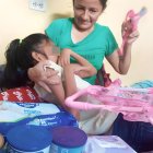 Con su hija en brazos, Mayra muestra las leches y otros insumos que compró gracias a los lectores.