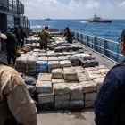 Recreación mediante IA de bultos sospechosos siendo inspeccionados en una embarcación en altamar durante un operativo contra el narcotráfico.