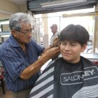 Don Jorge Barros le corta el cabello a Nicolás, quien prefiere la tijera frente a las tendencias actuales.