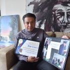Jonnathan Carrera con varias fotos y placas de los reconocimientos que recibió su padre por el aporte para dar identidad, normativa y masificación del ecuavóley