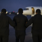 Traslado de un detenido hacia un avión bajo custodia en pista aeroportuaria nocturna, en recreación de IA.